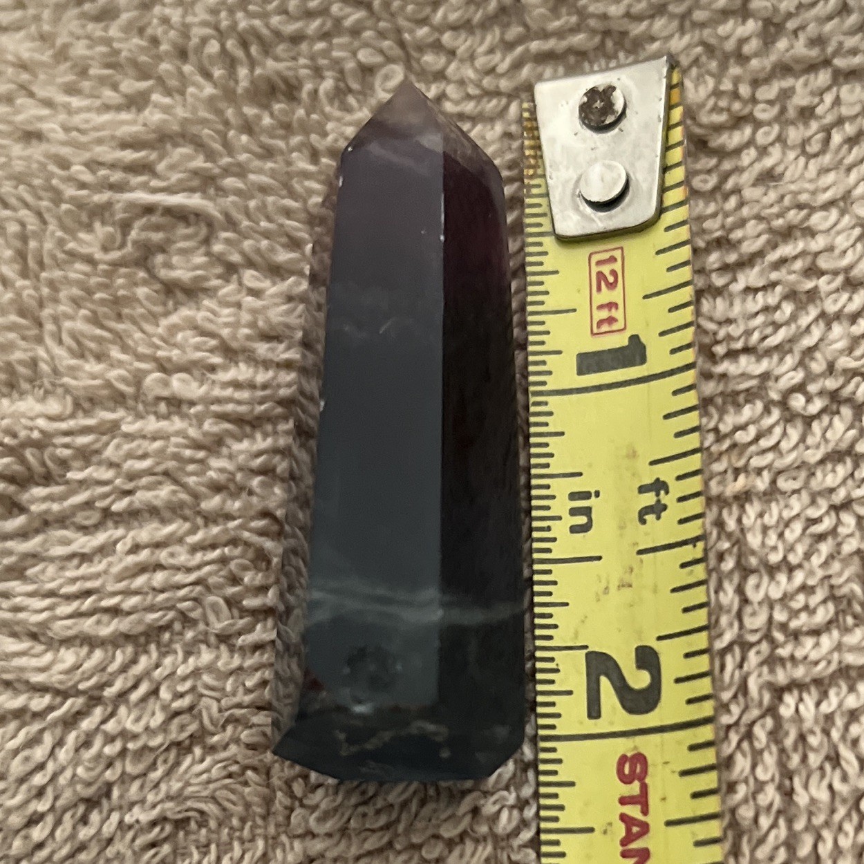 A polished rainbow fluorite crystal wand featuring distinct purple,blue,green
